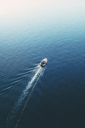 Top view of a white boat sailing in the blue seaの写真素材