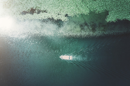 Boat floating on the water covered with green algae on a sunny dayの写真素材