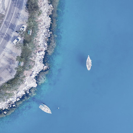 White boats near the shore with an automobile road