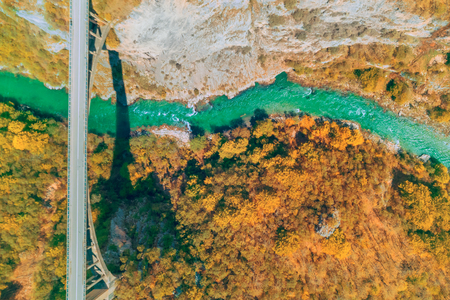 Autumn forest and a bridge over a river in the mountains, top viewの写真素材