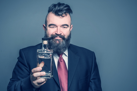 Adult bearded man in suit holding a bottle of alcoholの写真素材