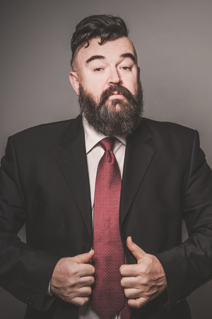 Adult bearded man in a suit and red tieの写真素材