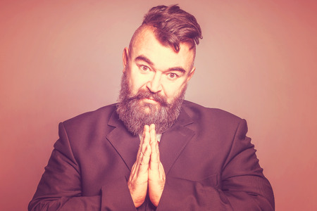 Imploring adult bearded man in a suit on a red background. Tonedの写真素材