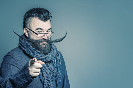 Adult bearded man in a scarf with a long mustache showing the forefinger forward. Tonedの写真素材