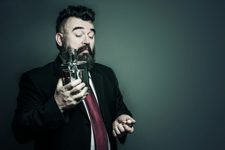 Adult bearded man in suit looking at a bottle of alcohol. Tonedの写真素材