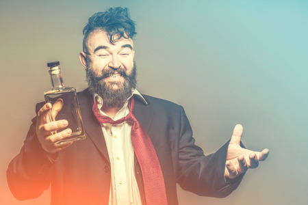 Smiling Drunk bearded man in suit with a bottle of alcohol in his hand. Toned