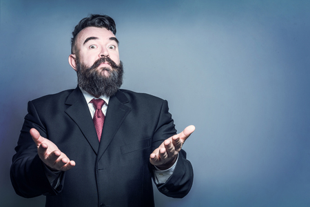 Adult bearded man in a suit helpless gesture on a blue backgroundの写真素材