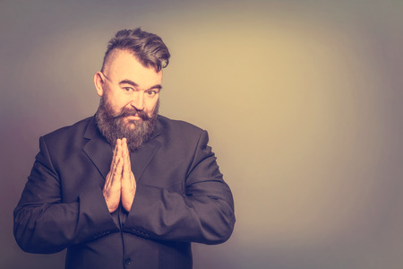 Imploring adult bearded man in a suit on a brown background. Tonedの写真素材