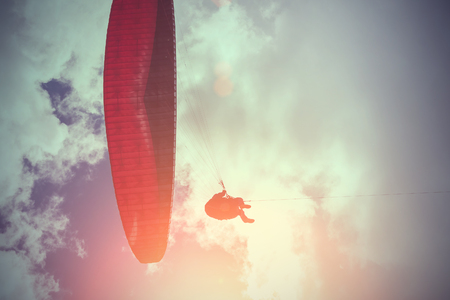 Red and black paraglider flying in the sky. Tonedの写真素材