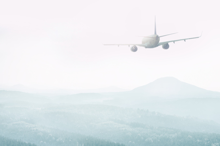 Airplane flying over the mountains in the fogの写真素材