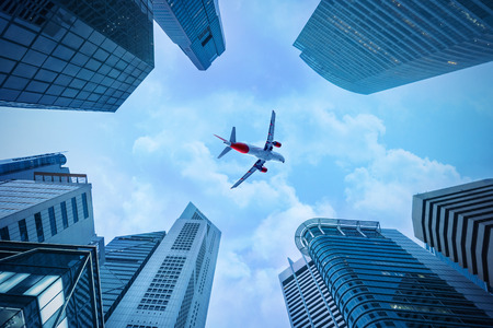 Airplane flying over skyscrapers, view of a bottom-upの写真素材