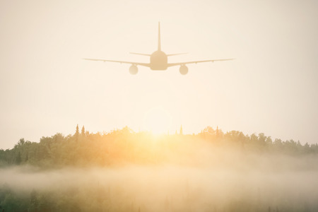 Airplane flying over foggy forestの写真素材