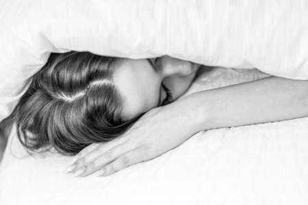 The woman hid under the covers on the bed. Sleep under a blanket. good night