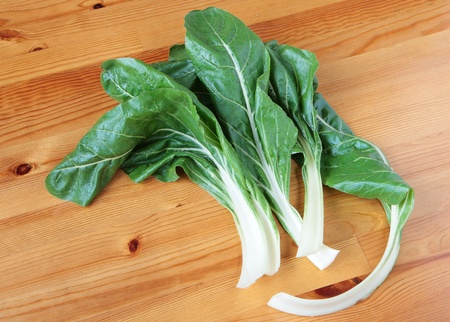 Chard leaves in water drops on a wooden table