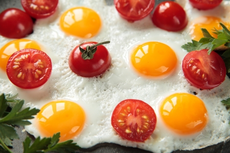 Fried quail eggs with tomatoes and parsleyの写真素材