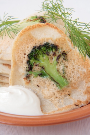 Pancakes with broccoli, dill and sour cream on plateの写真素材