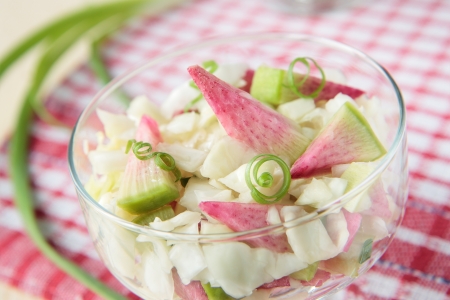 Pink radish salad with cabbage and green onions in glassの写真素材