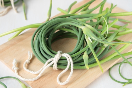 A bunch of stalks of garlic on a wooden boardの写真素材