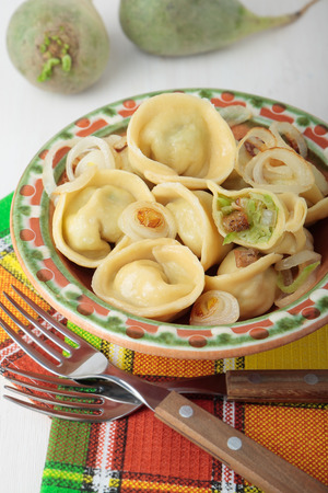 Dumplings with green radish, bacon and fried onions on a plateの写真素材