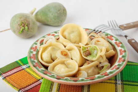 Dumplings with green radish, bacon and fried onions on a plateの写真素材