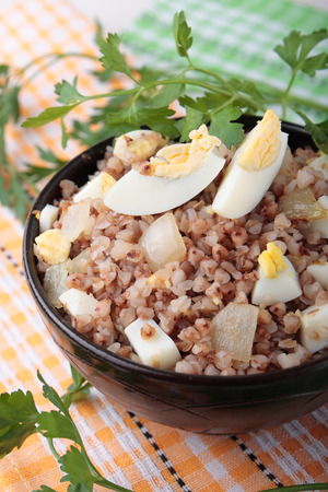 Buckwheat porridge with fried onions and boiled eggs in a bowlの写真素材