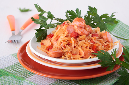 Sauerkraut, stewed with tomatoes, onions and sausage on a plateの写真素材