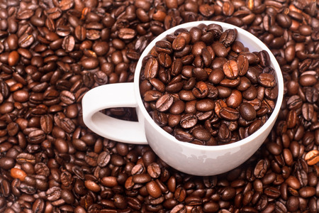 Closeup of white coffee cup full of coffee beansの写真素材