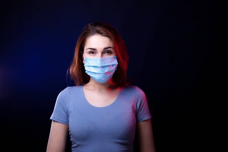Portrait of confident woman wearing medical protective mask. Studio shot. Black backgroundの写真素材