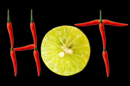 Fresh red peppers and sliced lemon isolated on black background.の写真素材