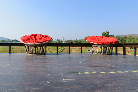 Rattan chair on the terrace with the backdrop of the field.の写真素材