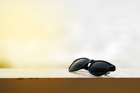 Black sunglasses resting on the balcony with an ocean backdrop.の写真素材