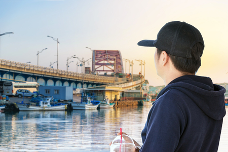 Back view of young man wearing a black cap and long sleeve blue looking  to the bridge.の写真素材