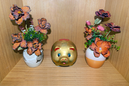 Vase plastic flower and piggy bank on wood background.の写真素材