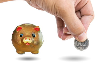 Woman's hand inserting coins into a piggy bank,concept for business finance background.の写真素材