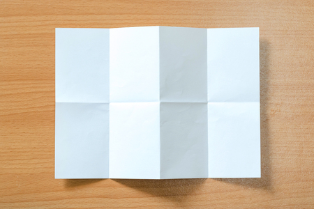 White paper with folds isolated on a wooden floor.の写真素材