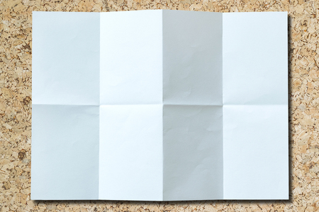 White paper with folds isolated on a wooden floor.