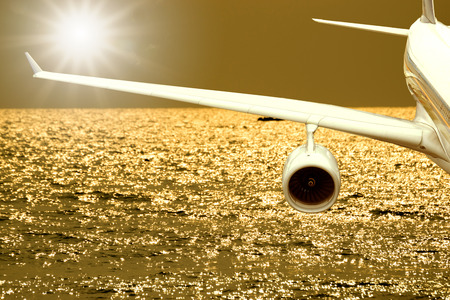 View of airplane wings while flying over the sea with beautiful sunshine.の写真素材