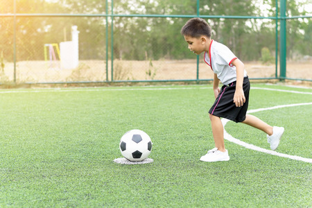 The boy was playing soccer on the football field with happiness.の写真素材