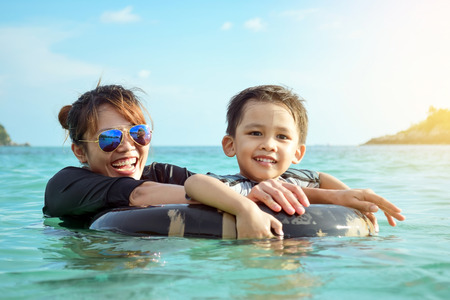 Mother and son playing in the sea and laughing happily in a weekend.の写真素材