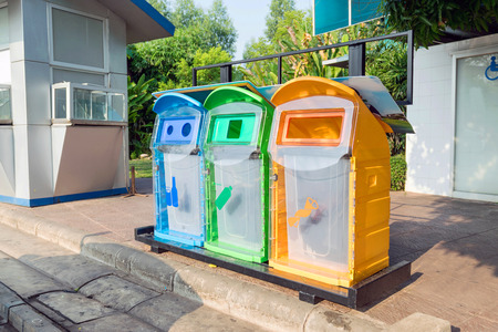 Colorful plastic bins for different waste types in the park.の写真素材