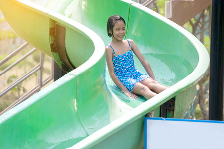 Asian girl have fun to playing a slide in the water park.の写真素材