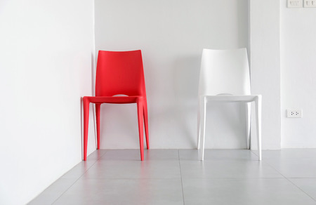 Red and white plastic chairs at the corner of the white room.の写真素材