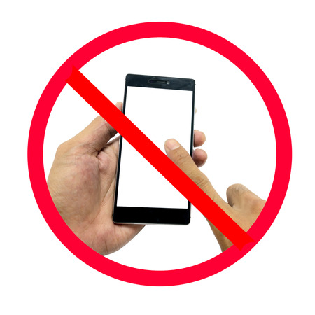 Hand holding smart phone with do not use smart phone sign isolated on white background.の写真素材