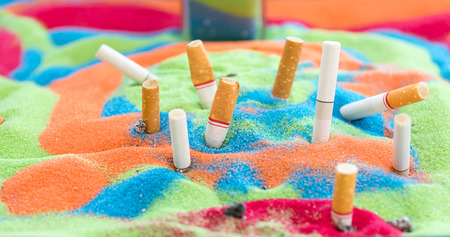 Smoked cigarettes in the sand beautiful colors  in the ashtray.の写真素材