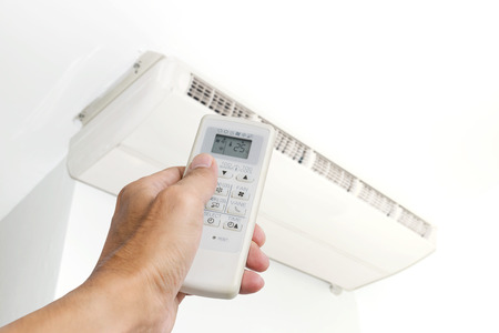Hand holding the remote control to control the air conditioning isolated on white background.の写真素材
