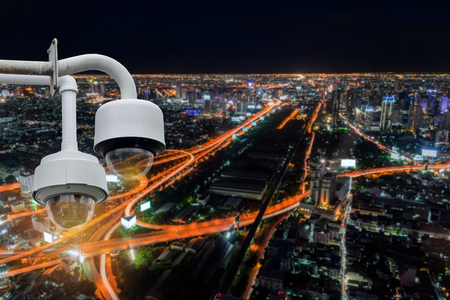 Closeup CCTV camera outdoors with colorful night cityscape background.の写真素材