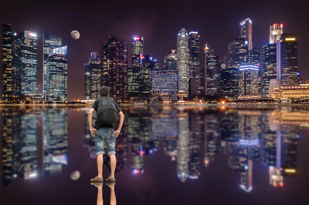 Backpacker standing and looking to the beautiful skyscraper with water reflection.の写真素材