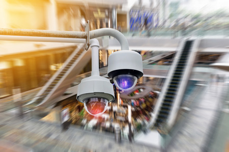 Closeup CCTV security camera on blurred inside shopping mall background.の写真素材