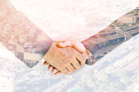 Double exposure handshake of business peoples on the top view of cityscape background.の写真素材
