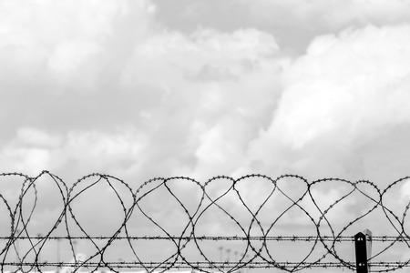 Closeup fence barbed wire with clouds sky background.の写真素材